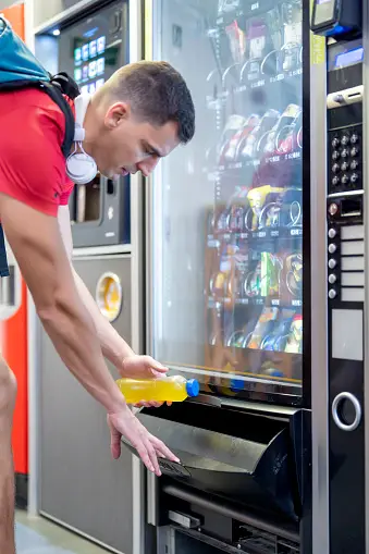 Worker purchasing a snack for break time in murfreesboro tn. smart vending machine provided by alata amenities.